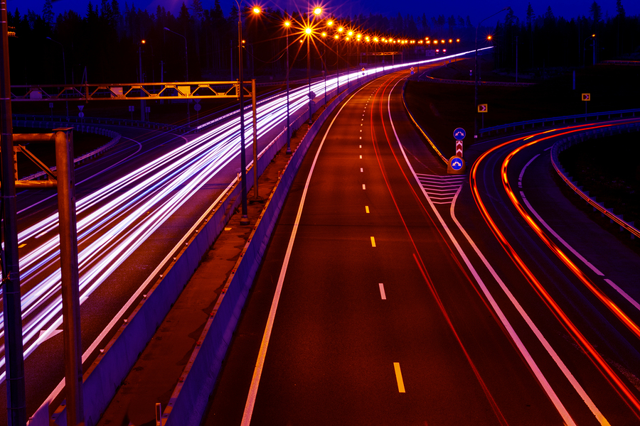 Cars light trails on a curved highway at night. Night traffic trails. Motion blur. Night city road with traffic headlight motion. Cityscape. Light up road by vehicle motion blur.