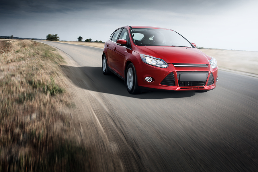 Red car Ford Focus III Sport fast speed driving on the apshalt road at daytime