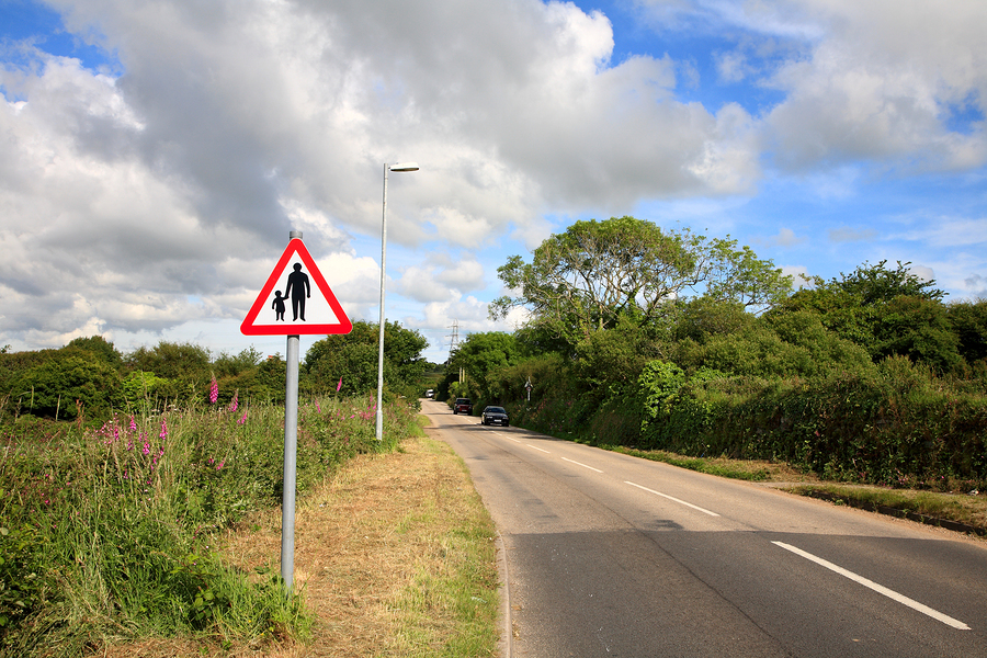 Country road and pedestrians in road sign, Cornwall, UK.